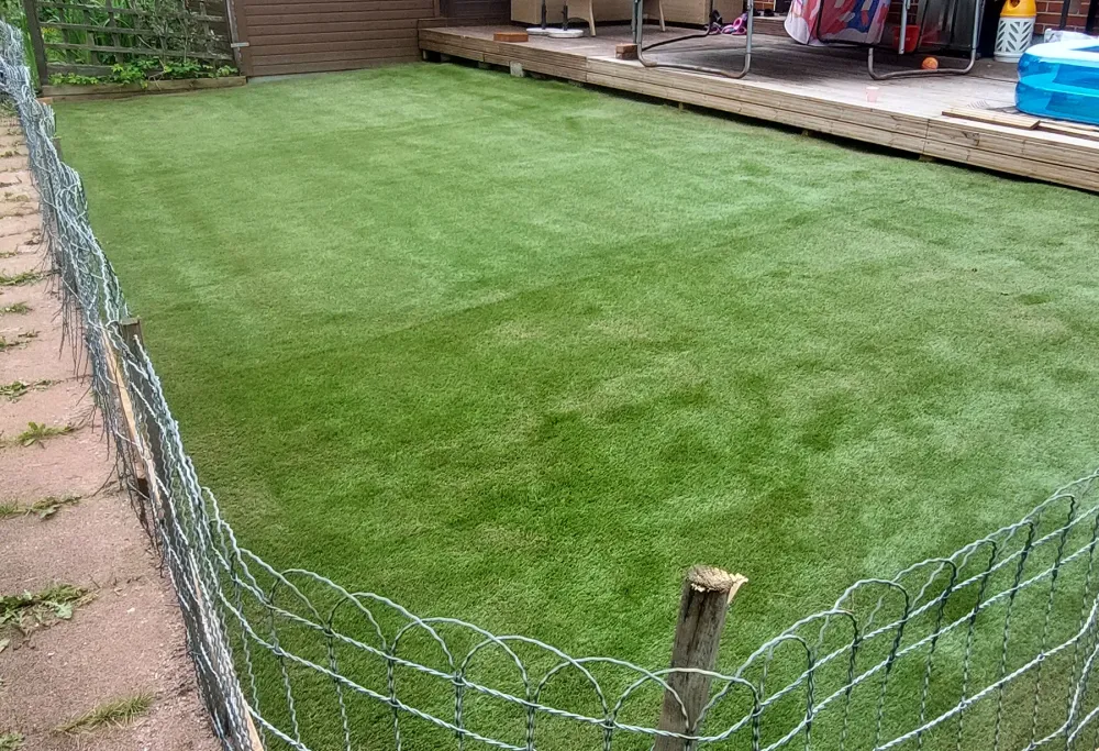 Koira nauttii puhtaasta ja kestävästä tekonurmesta pihalla